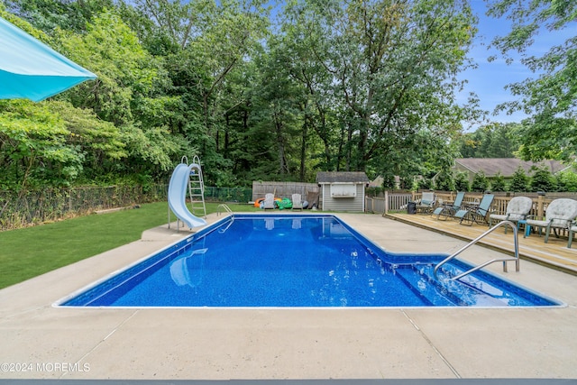 view of pool featuring a storage shed, a water slide, and a deck