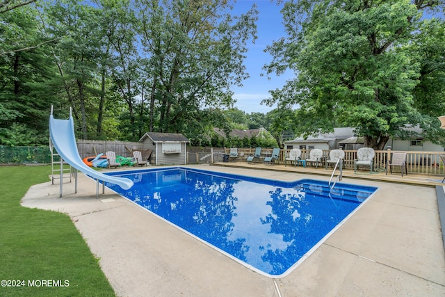 view of swimming pool featuring a water slide and a storage shed