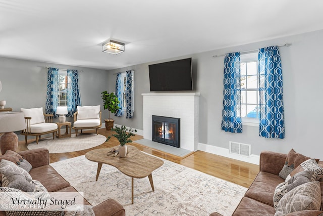 living room with hardwood / wood-style floors and a brick fireplace