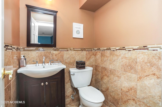 bathroom featuring vanity, toilet, and tile walls