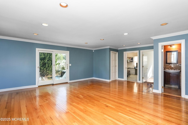 unfurnished living room with ornamental molding, sink, and light wood-type flooring