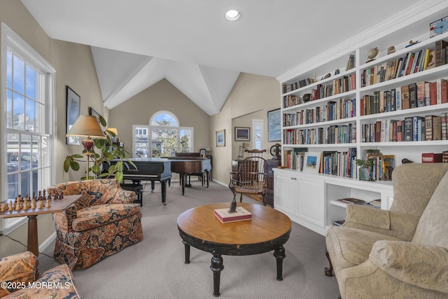 sitting room with vaulted ceiling, light carpet, and built in shelves