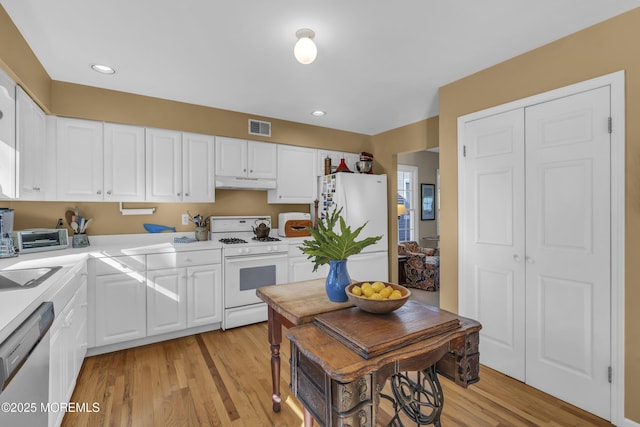 kitchen with white cabinetry, white appliances, and light wood-type flooring