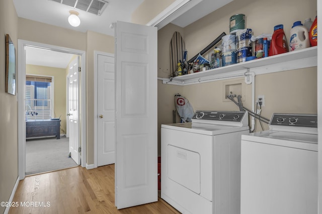 clothes washing area featuring light hardwood / wood-style floors and washing machine and clothes dryer