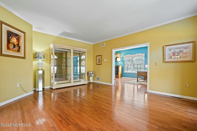 unfurnished room featuring ornamental molding and light hardwood / wood-style flooring