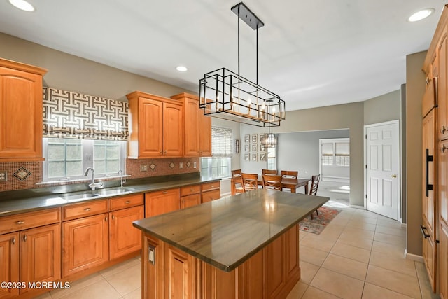 kitchen featuring a kitchen island, decorative light fixtures, tasteful backsplash, sink, and a healthy amount of sunlight