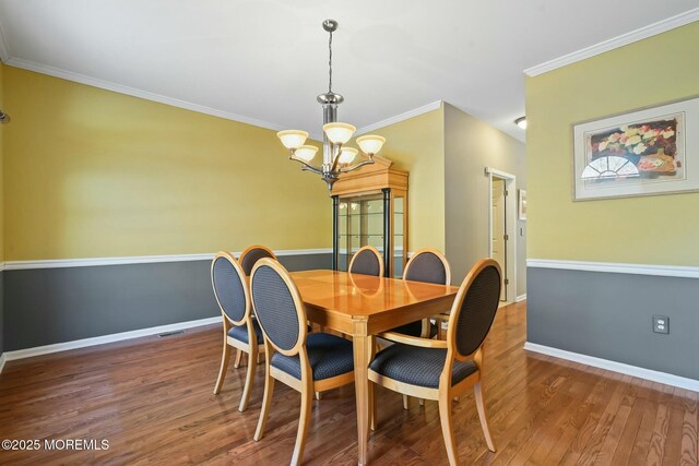 dining room featuring an inviting chandelier, ornamental molding, and dark wood-type flooring