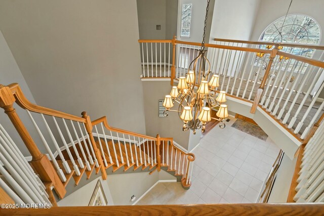 stairs with a wealth of natural light, tile patterned floors, and a chandelier