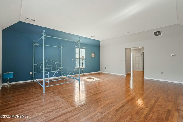 unfurnished living room with hardwood / wood-style floors and vaulted ceiling