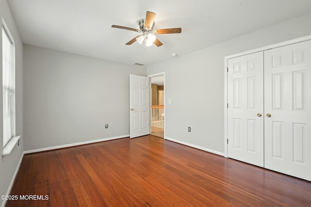 unfurnished bedroom featuring hardwood / wood-style floors, ceiling fan, and a closet