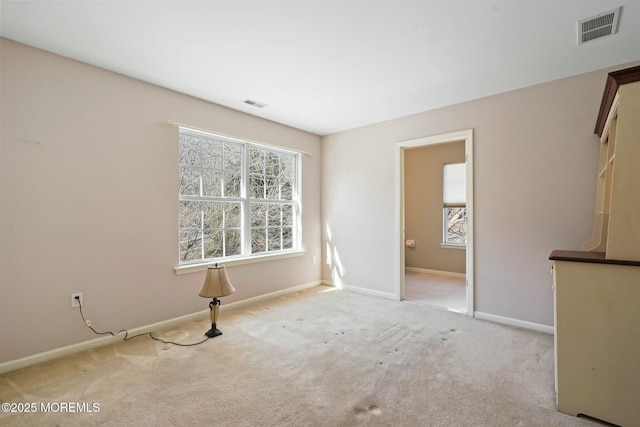 unfurnished room featuring plenty of natural light and light carpet