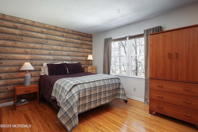 bedroom featuring a textured ceiling, light wood-style flooring, and baseboards