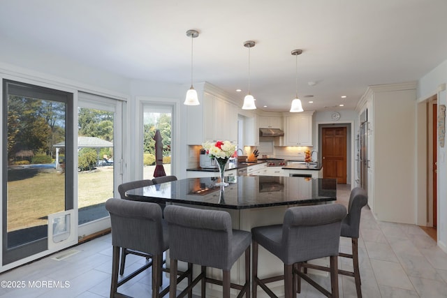 kitchen featuring decorative light fixtures, recessed lighting, decorative backsplash, white cabinetry, and under cabinet range hood