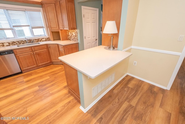 kitchen featuring dishwasher, sink, backsplash, kitchen peninsula, and light wood-type flooring