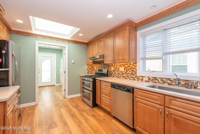 kitchen with sink, crown molding, stainless steel appliances, light hardwood / wood-style floors, and decorative backsplash