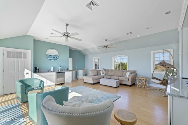 living room with vaulted ceiling, ceiling fan, and light wood-type flooring