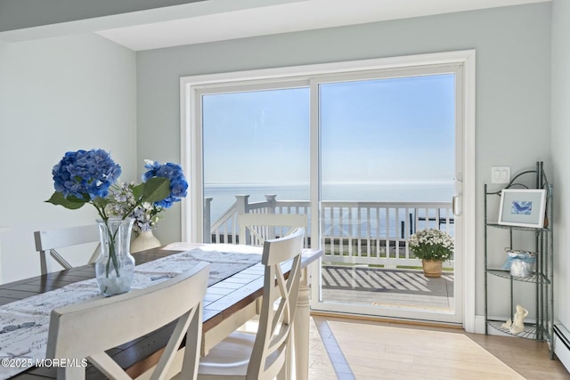 dining space with a water view and light hardwood / wood-style flooring