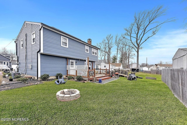 rear view of house featuring an outdoor fire pit and a lawn