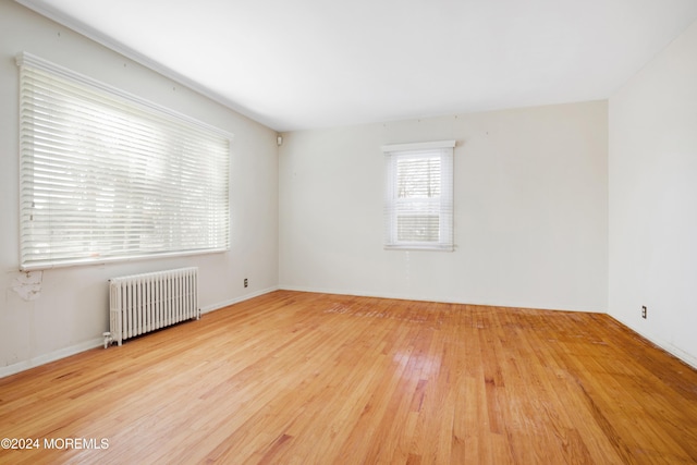 unfurnished room with radiator and hardwood / wood-style floors