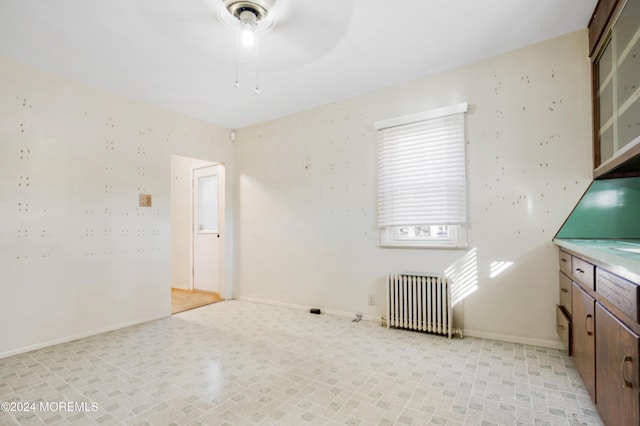 unfurnished room featuring ceiling fan and radiator heating unit