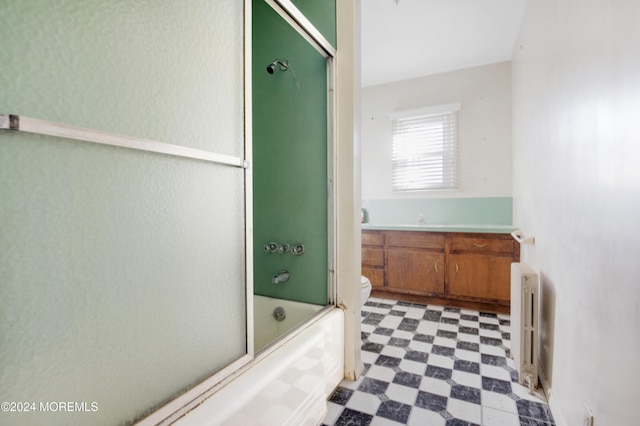 full bathroom featuring shower / bath combination with glass door, radiator, toilet, and vanity