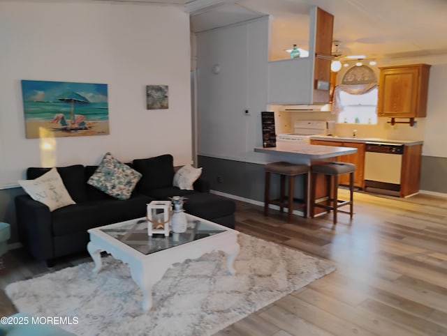 living area featuring light wood-style flooring, baseboards, and ceiling fan