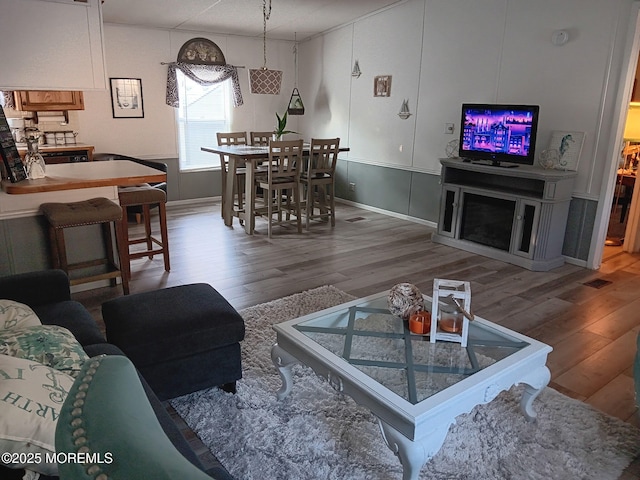 living area with visible vents and wood finished floors
