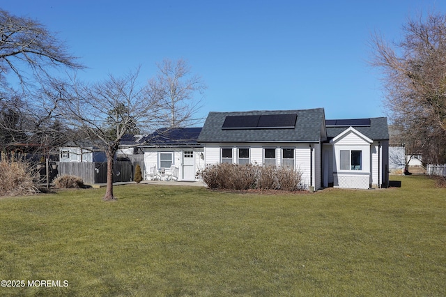 rear view of property featuring a yard, a patio area, and solar panels