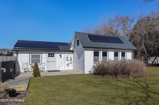 rear view of house featuring a yard and solar panels