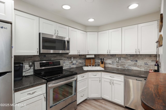 kitchen with white cabinetry, sink, tasteful backsplash, and stainless steel appliances