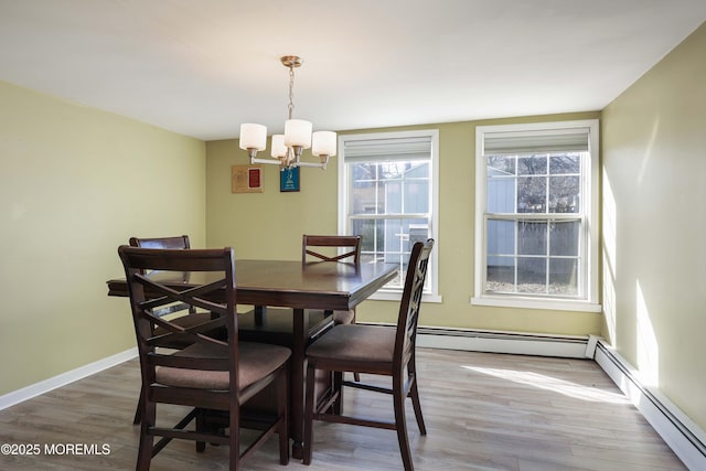 dining room with a baseboard heating unit, hardwood / wood-style flooring, and a notable chandelier