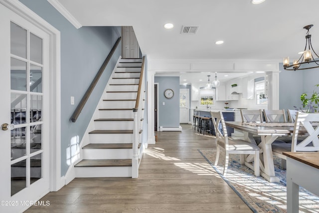 dining space featuring a baseboard heating unit, dark hardwood / wood-style flooring, crown molding, and a notable chandelier