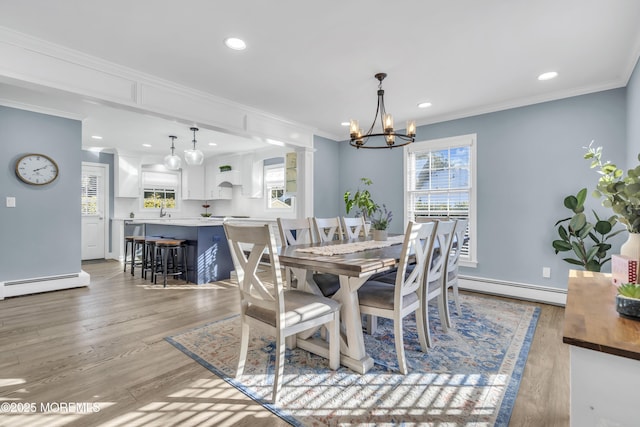 dining room featuring a baseboard heating unit, ornamental molding, a notable chandelier, and light wood-type flooring