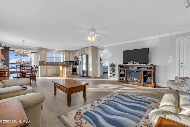 living room with crown molding, ceiling fan with notable chandelier, and light hardwood / wood-style floors