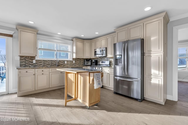 kitchen featuring appliances with stainless steel finishes, a center island, decorative backsplash, and cream cabinetry