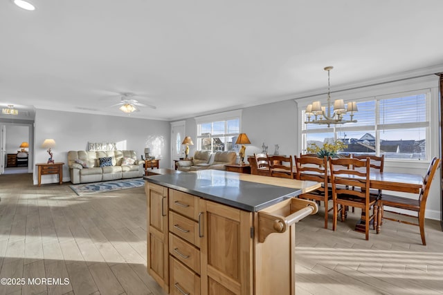 kitchen featuring hanging light fixtures, crown molding, ceiling fan with notable chandelier, and a center island