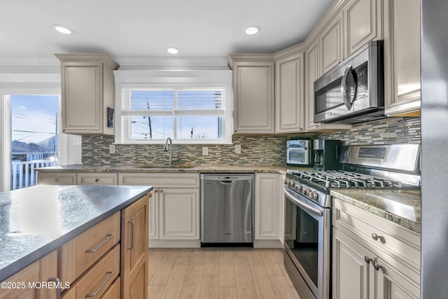 kitchen featuring sink, stainless steel appliances, tasteful backsplash, ornamental molding, and light wood-type flooring