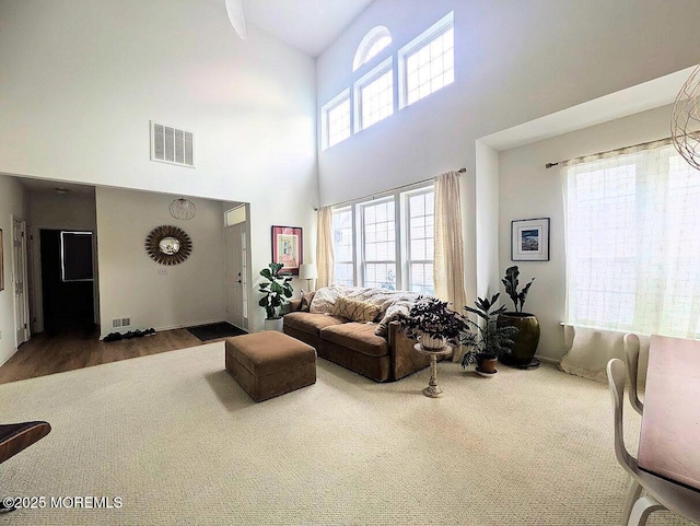 living room with a towering ceiling and carpet flooring