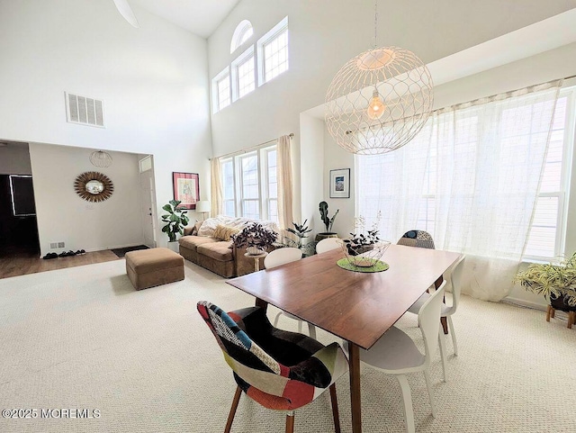 carpeted dining area with a towering ceiling