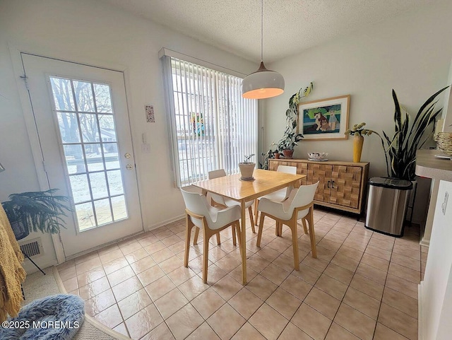 dining space with a textured ceiling and light tile patterned flooring