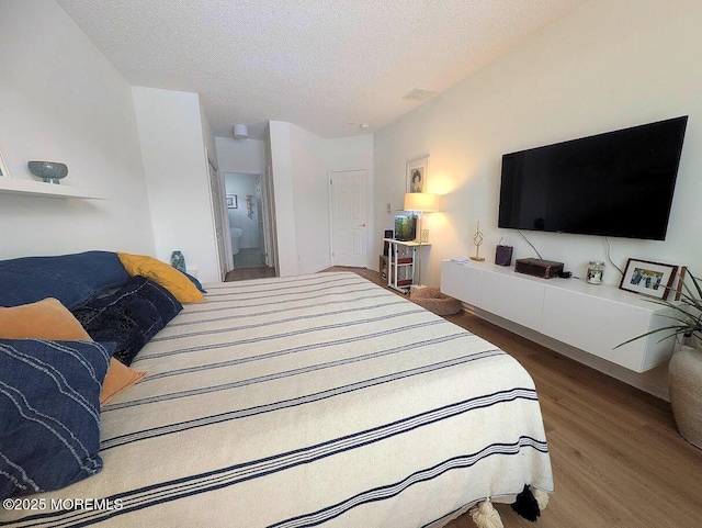 bedroom with hardwood / wood-style flooring, connected bathroom, and a textured ceiling