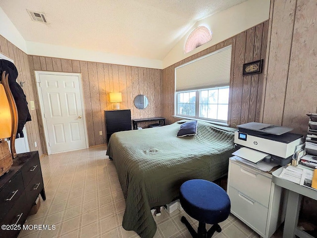 bedroom with vaulted ceiling, wooden walls, and a textured ceiling