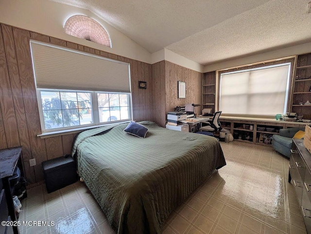 bedroom with wood walls, a textured ceiling, and vaulted ceiling