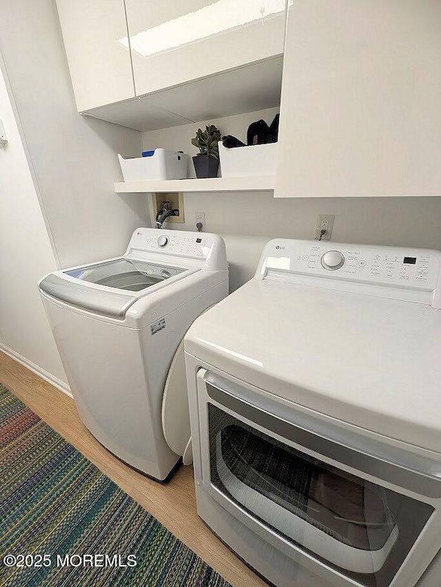 laundry area with light hardwood / wood-style floors and washing machine and clothes dryer