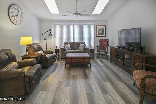 living room with dark wood-type flooring, vaulted ceiling with skylight, and ceiling fan