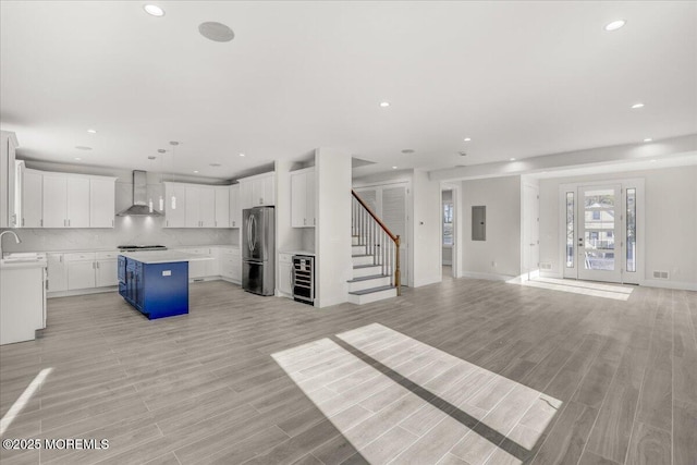 unfurnished living room featuring sink, beverage cooler, light wood-type flooring, and electric panel