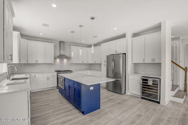 kitchen featuring a kitchen island, stainless steel refrigerator, blue cabinets, wine cooler, and wall chimney exhaust hood