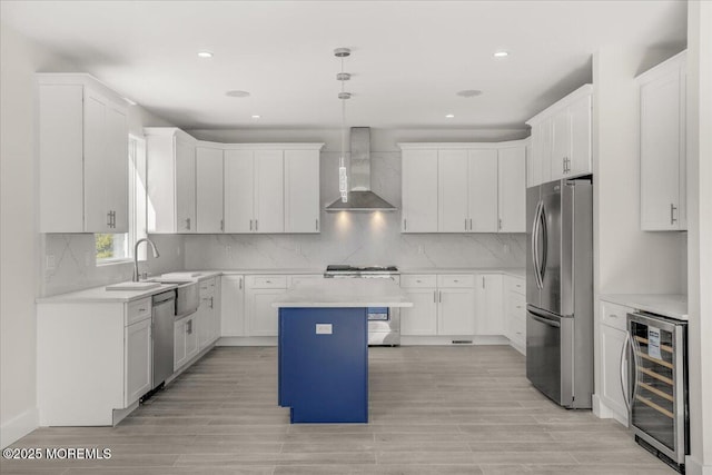 kitchen with a kitchen island, pendant lighting, beverage cooler, stainless steel appliances, and wall chimney exhaust hood