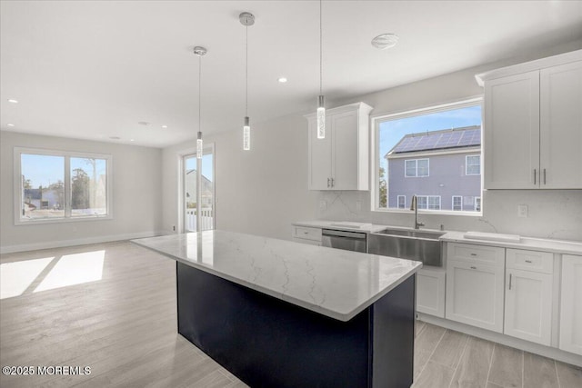 kitchen featuring pendant lighting, sink, white cabinetry, a center island, and stainless steel dishwasher