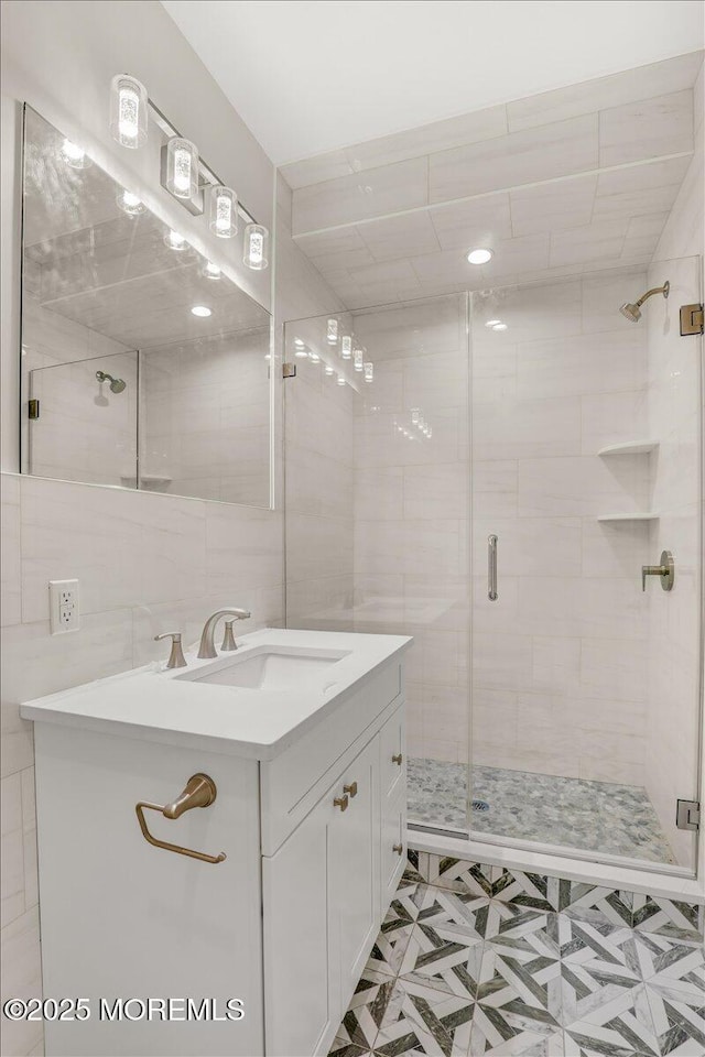 bathroom with vanity, an enclosed shower, and tile walls